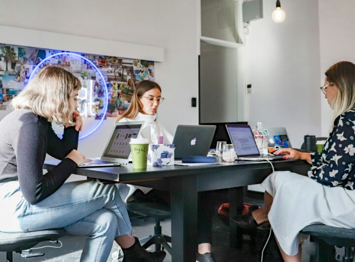 3 women sitting on chair in front of table with laptop computers