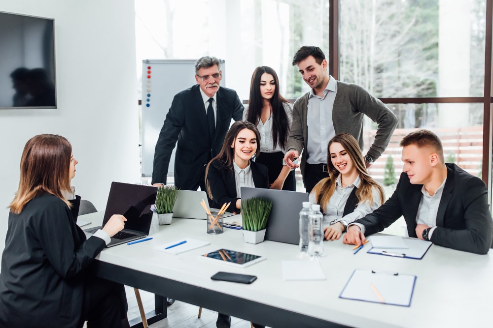 Une équipe diversifiée de professionnels collaborant activement dans un espace de bureau moderne et lumineux, illustrant le dynamisme de l'entreprise