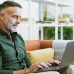 Laptop, research and businessman in office with contact, communication or email for creative project. Technology, reading and mature male editor with online article for publishing with computer.